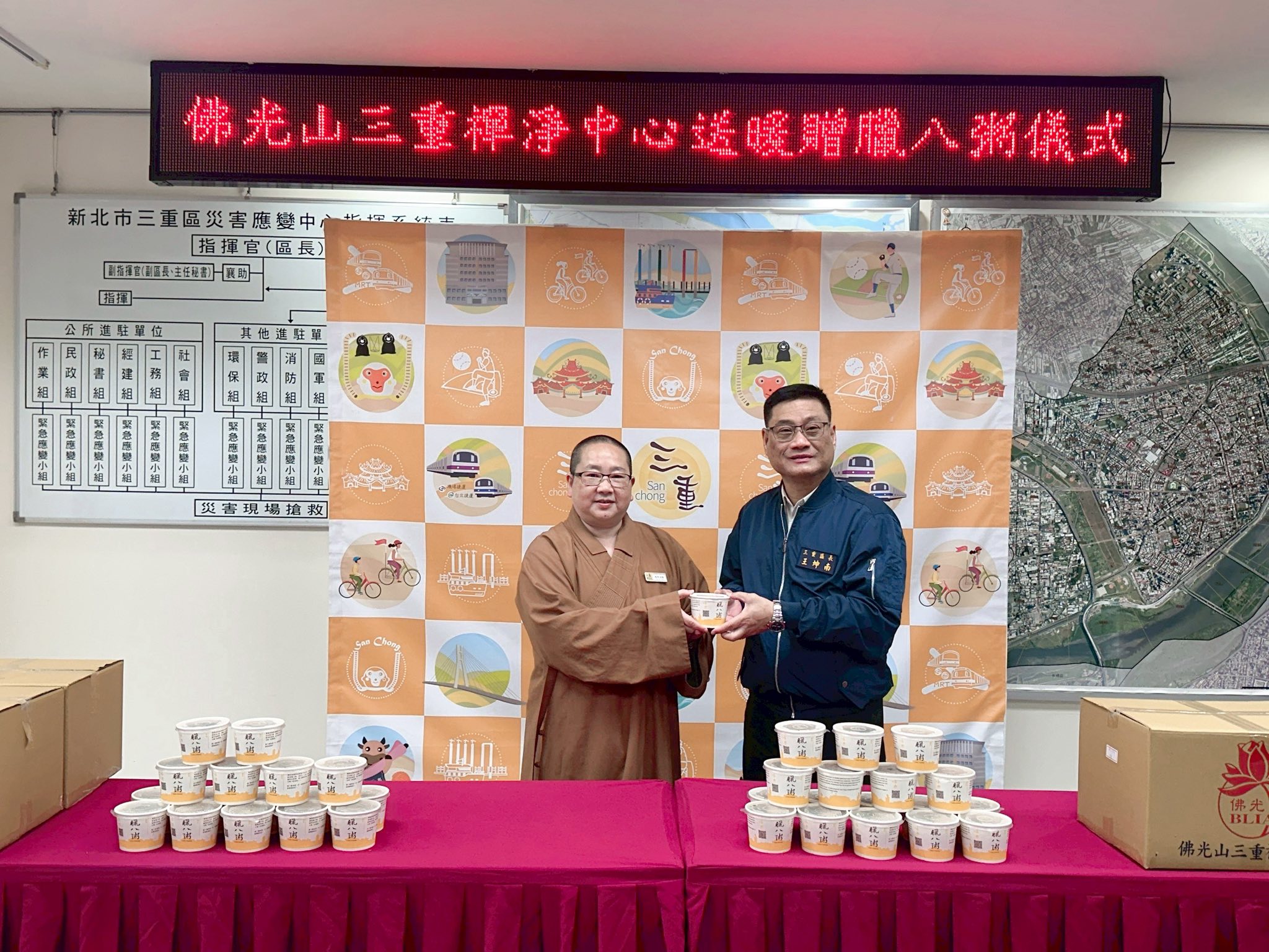 佛光山三重禪淨中心如宗法師(左)暖心贈500份臘八粥予三重區單位，由三重區長王坤南(右一)代表受贈。